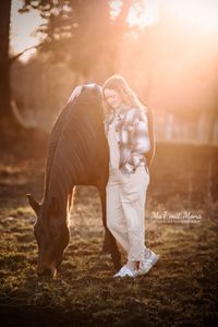 Foto-grasendes-Pferd-und-Frau-angelehtnt